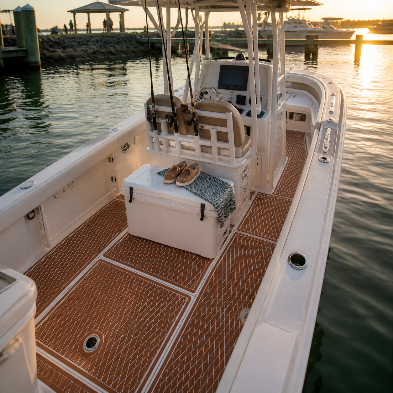 Center-console fishing boat cockpit with brown diamond-pattern flooring, rod holders, a cooler, and marina water at sunset