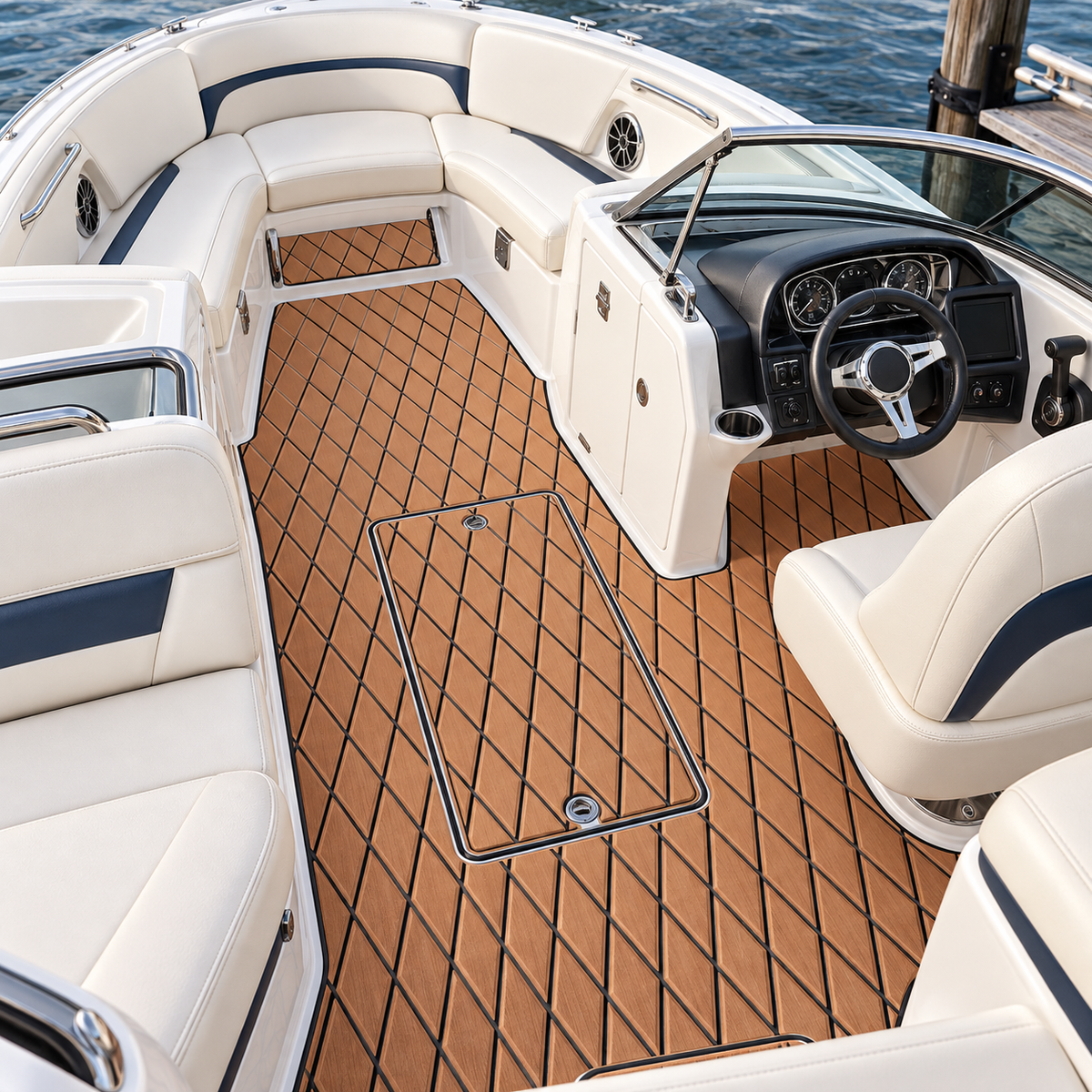 High-angle view of a white bowrider cockpit with tan and black diamond-pattern flooring around a central storage hatch, helm console, seats, and bow passage