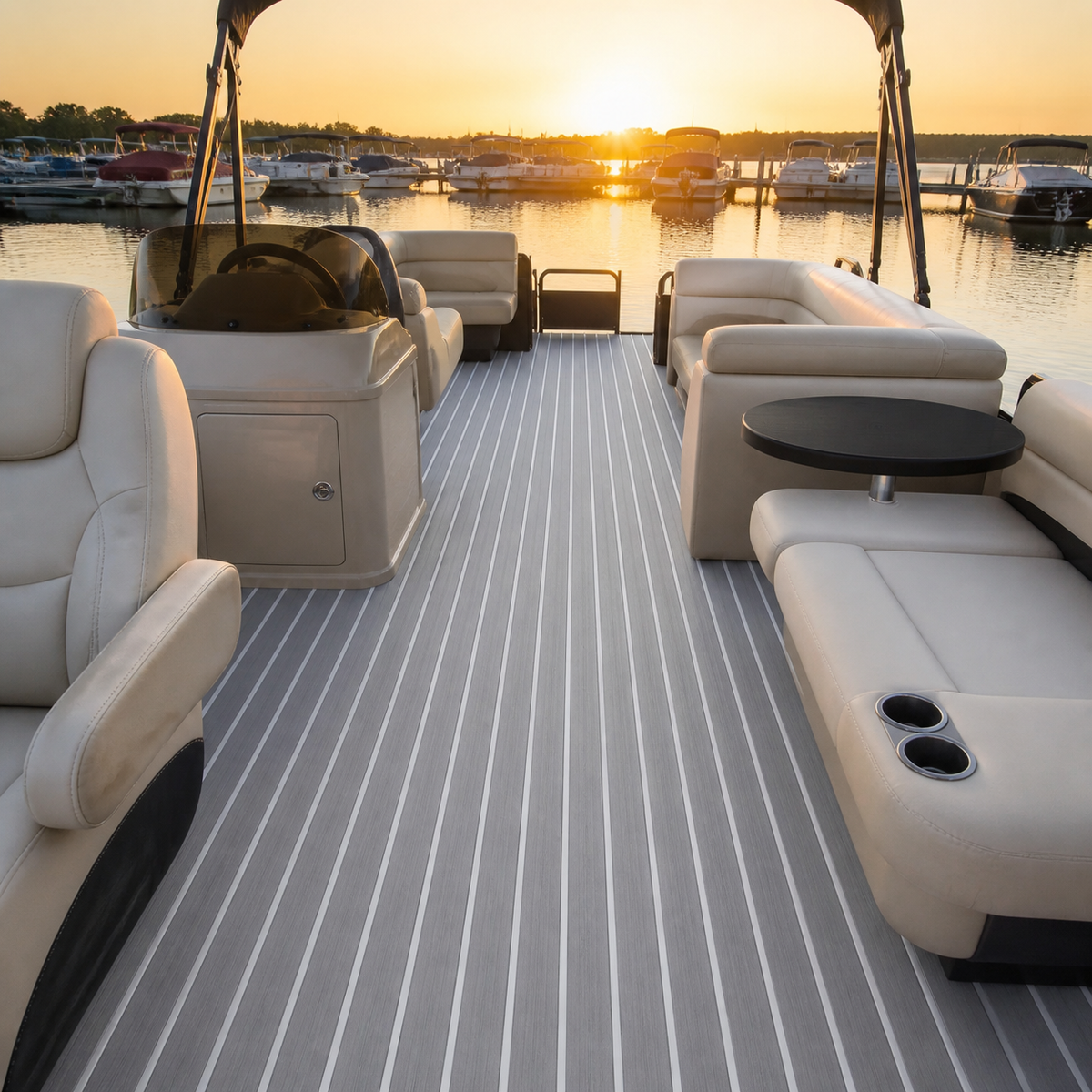 Pontoon boat interior at sunset with white lounge seating, a helm console, a black table, and gray flooring with white stripes