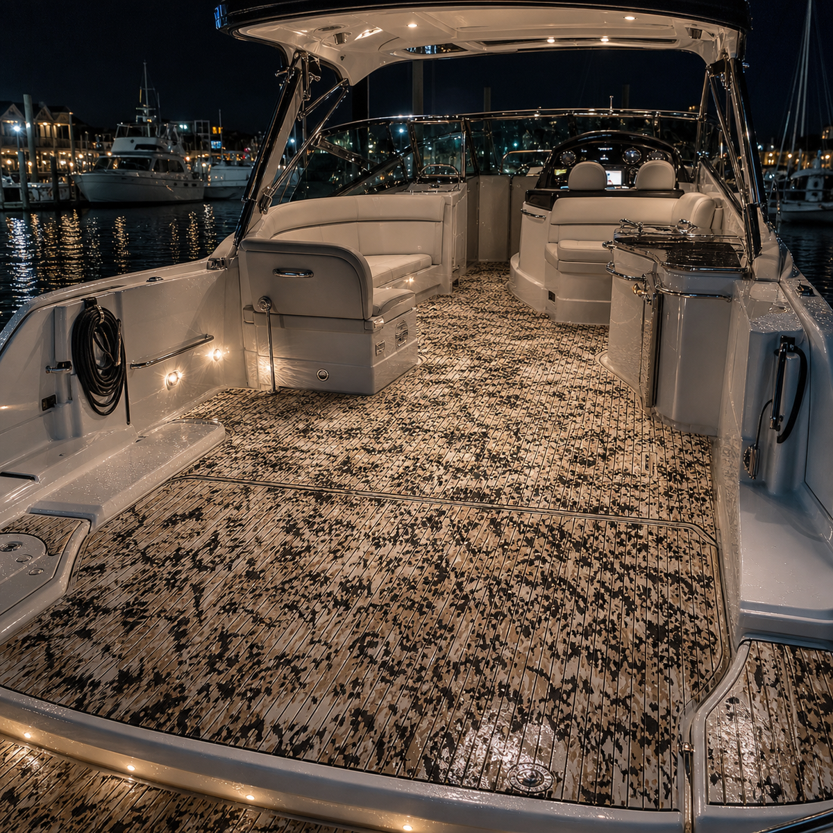 Tan-and-black patterned cockpit flooring on a cruiser at a marina at night, with white seating, a helm, a sink, and deck lights visible