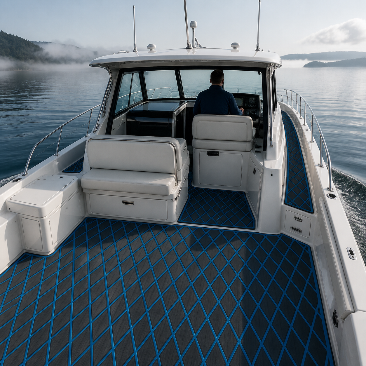 Cabin cruiser cockpit with dark gray flooring and blue diamond lines, white seating, a helmsman, calm water, and misty hills ahead